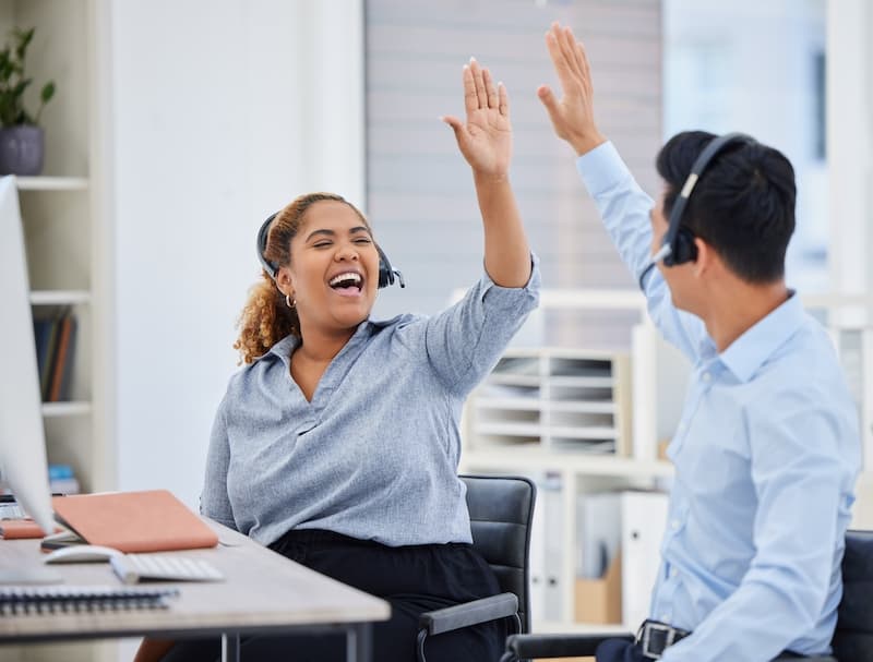 Two call centre workers high-fiving each other
