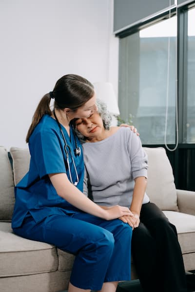An aged care nurse comforting an elderly patient