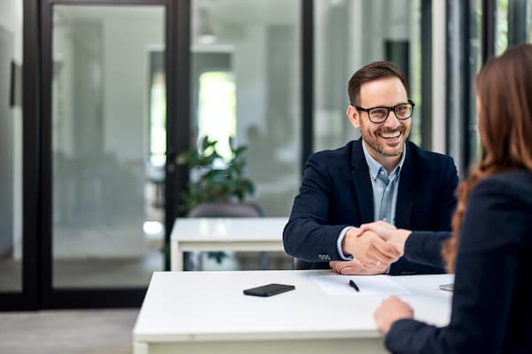 A sales consultant shaking hand and smiling after securing a deal in a modern office setting
