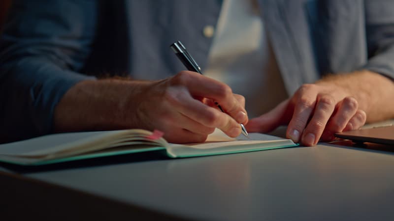 Close up of a man taking notes on a desk