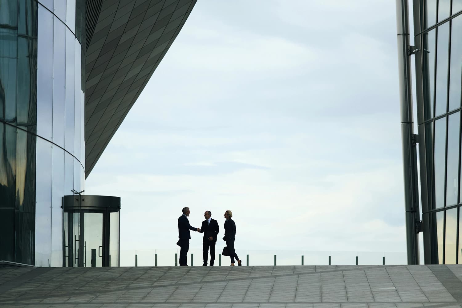 Two business men shake hands outside a modern building