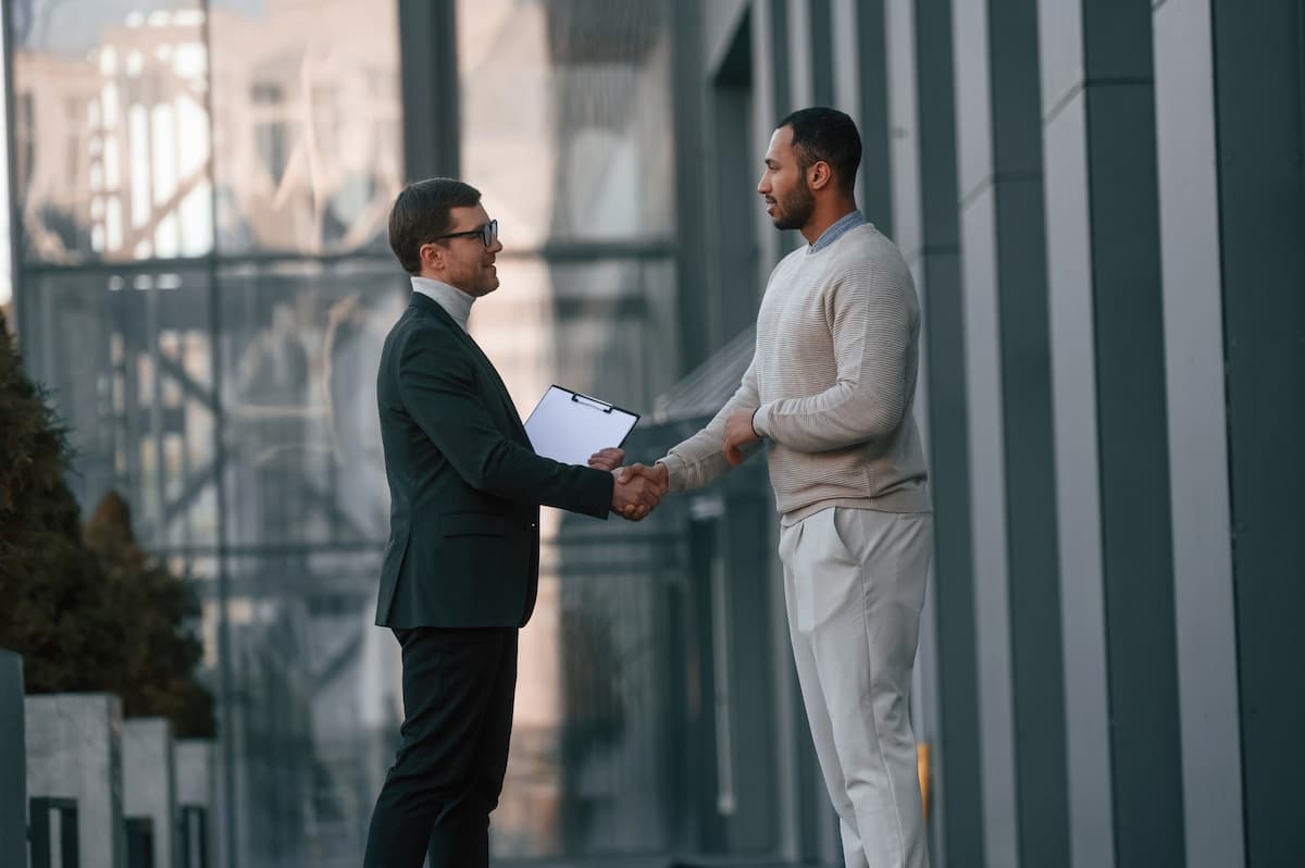 Two businessmen shaking hand outside a modern building