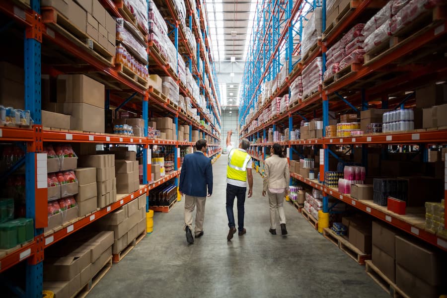 Managers and worker walking in a logistics warehouse and looking up