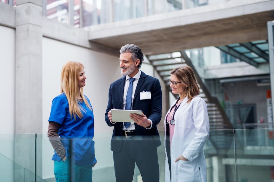 Medical Team Discussing Data on Tablet in Hospital